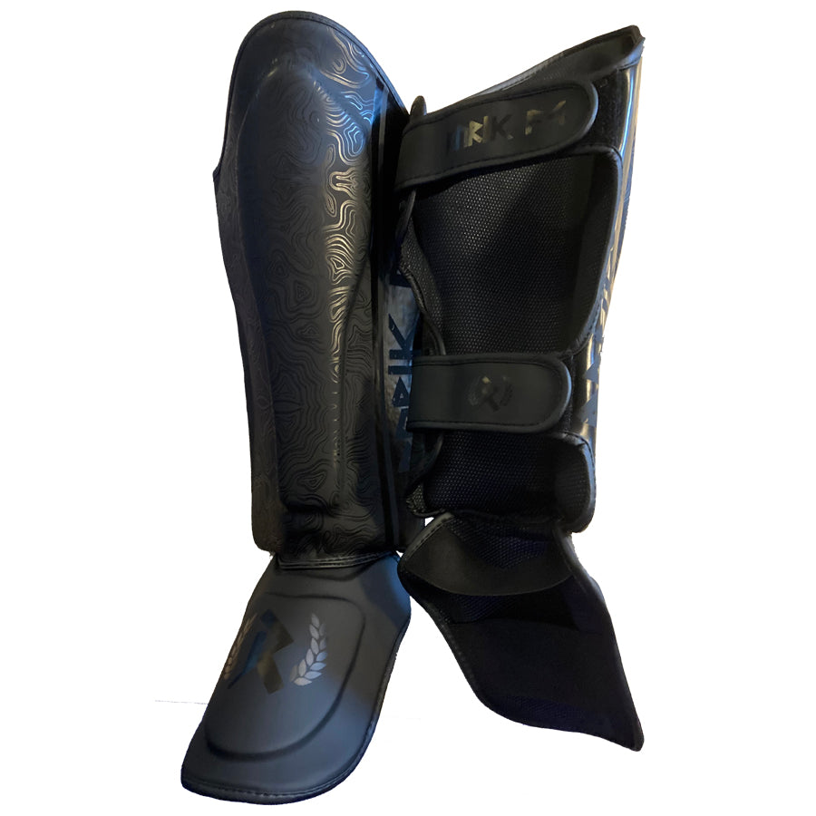Rurik Fightgear Grimnir säärisuojat on suunniteltu thainyrkkeilyyn ja potkunyrkkeilyyn. Ergonominen muotoilu, tehokas iskunvaimennus ja kestävät kiinnitykset. Kuvassa säärisuojat viistosti edestä ja takaa.