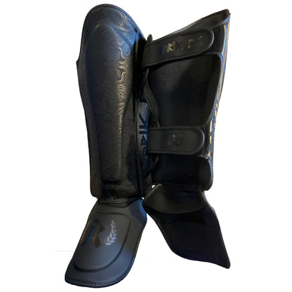 Rurik Fightgear Grimnir säärisuojat on suunniteltu thainyrkkeilyyn ja potkunyrkkeilyyn. Ergonominen muotoilu, tehokas iskunvaimennus ja kestävät kiinnitykset. Kuvassa säärisuojat viistosti edestä ja takaa.