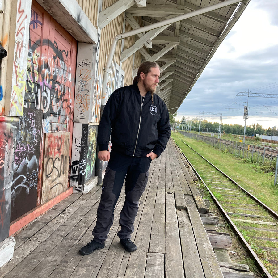Rurik Fightgear-lentäjänpusakka.
Rurik FG "R" -logo rintapielessä sekä riimulogo selässä monivärisesti brodeerattuna. Kuvassa pilottitakki  Mikan päällä. ptcumbat.com