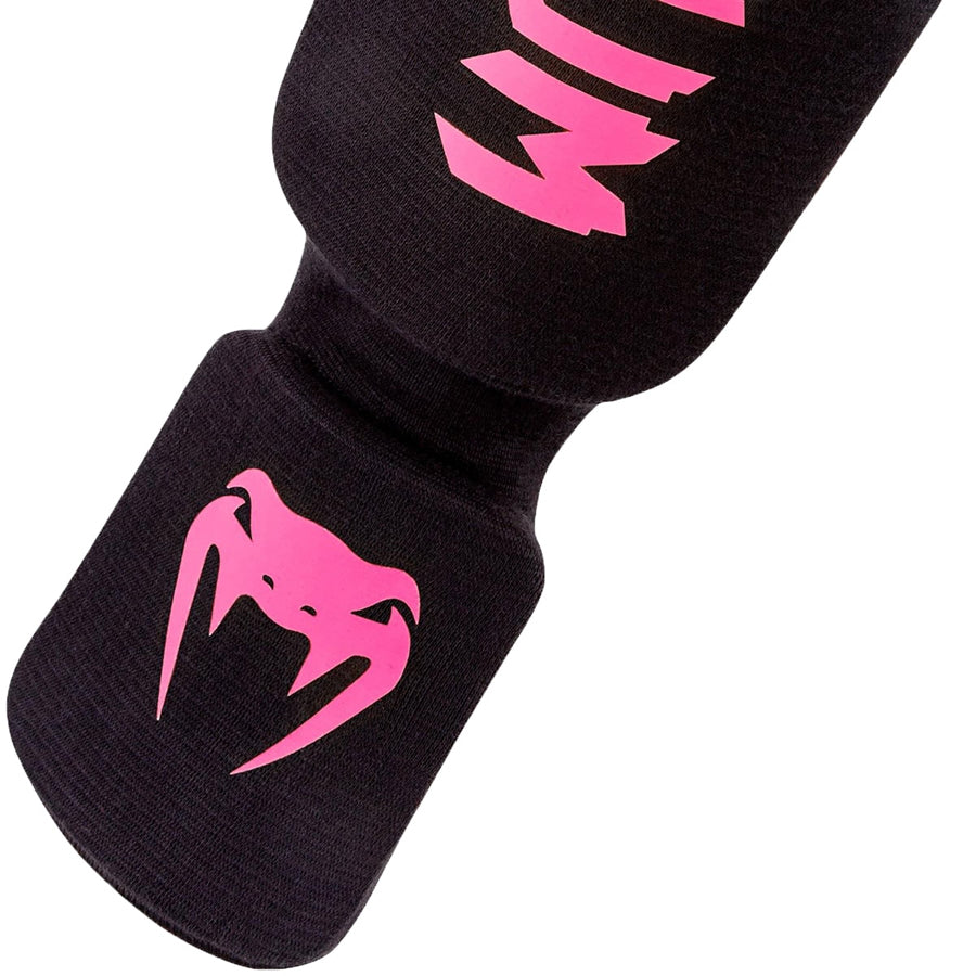 Venum Kontact -sukkamalliset slip-on säärisuojat. Kuvassa jalkateräosa, jossa pinkki venum-logo.  pt.combat.fi