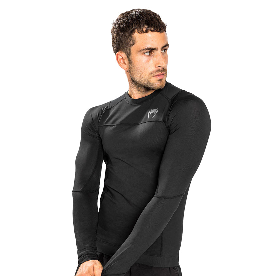 Venum G-Fit Air Long-Sleeve Rashguard. Tyylilkäs musta väri. Kuvassa rashguard kuvattuna viistosti miehen päällä. ptcumbat.com